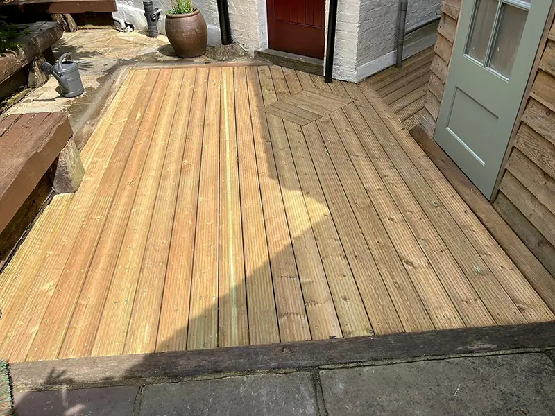 Deck installation costs: board cuts and finishing details Timber decking fitted around doorways with changes in board direction and shaped edges