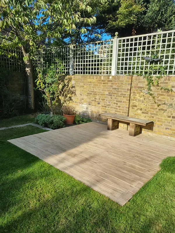 DIY decking budget: a simple, compact layout Small rectangular timber deck with a bench beside a brick garden wall and lawn
