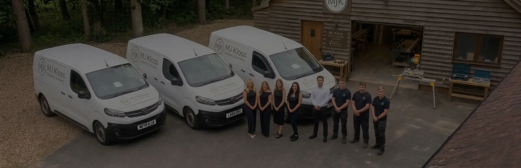 MJ Kloss team standing beside branded vans outside a timber workshop